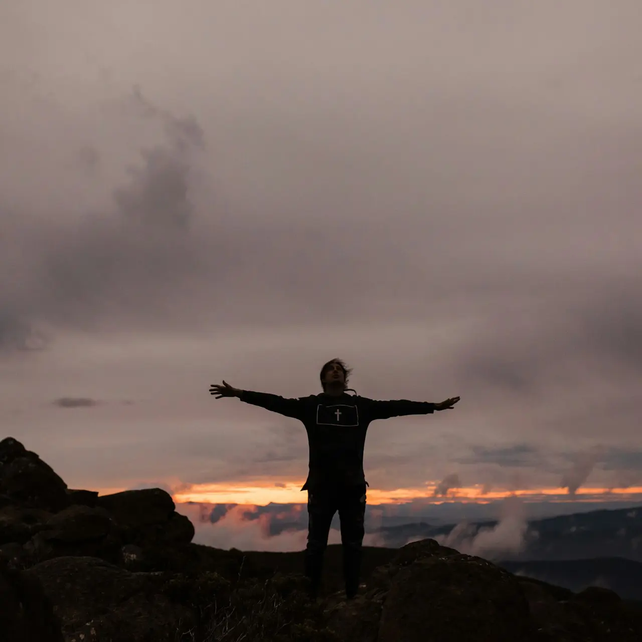 man standing on rock formation under cloudy sky during daytime