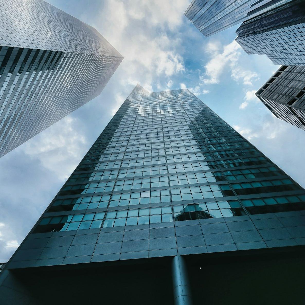 low angle photography of high rise building under white clouds during daytime