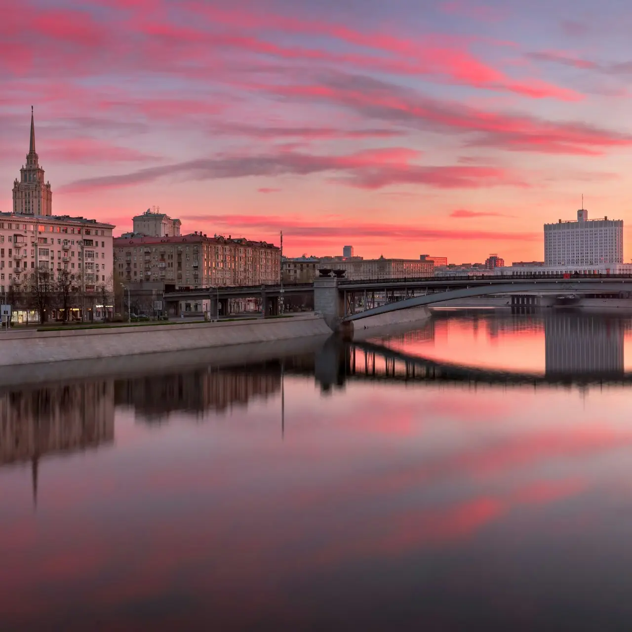 body of water near city buildings during sunset